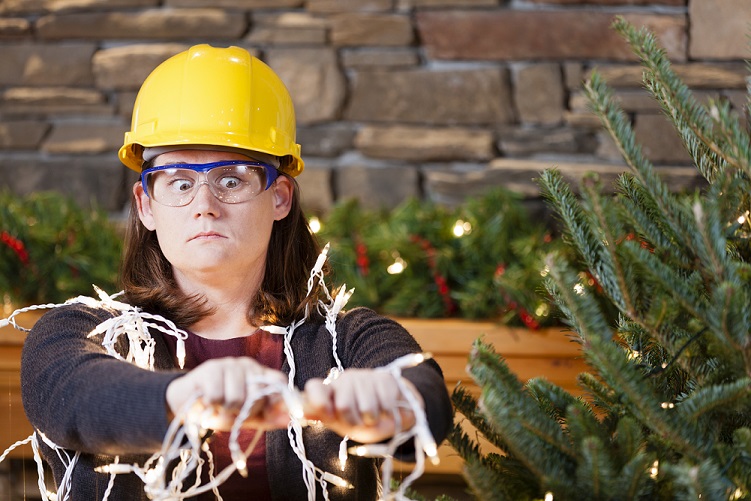 Young woman wearing hardhat and safety glasses plugging in Christmas tree lights