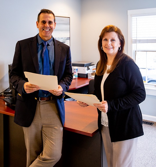 man and woman standing in an office smiling