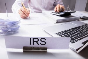 IRS nameplate on a desk in front of man