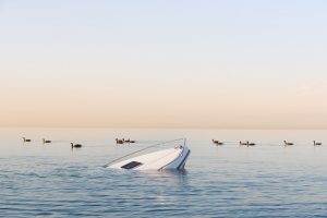 modern white boat sinking in water after crash